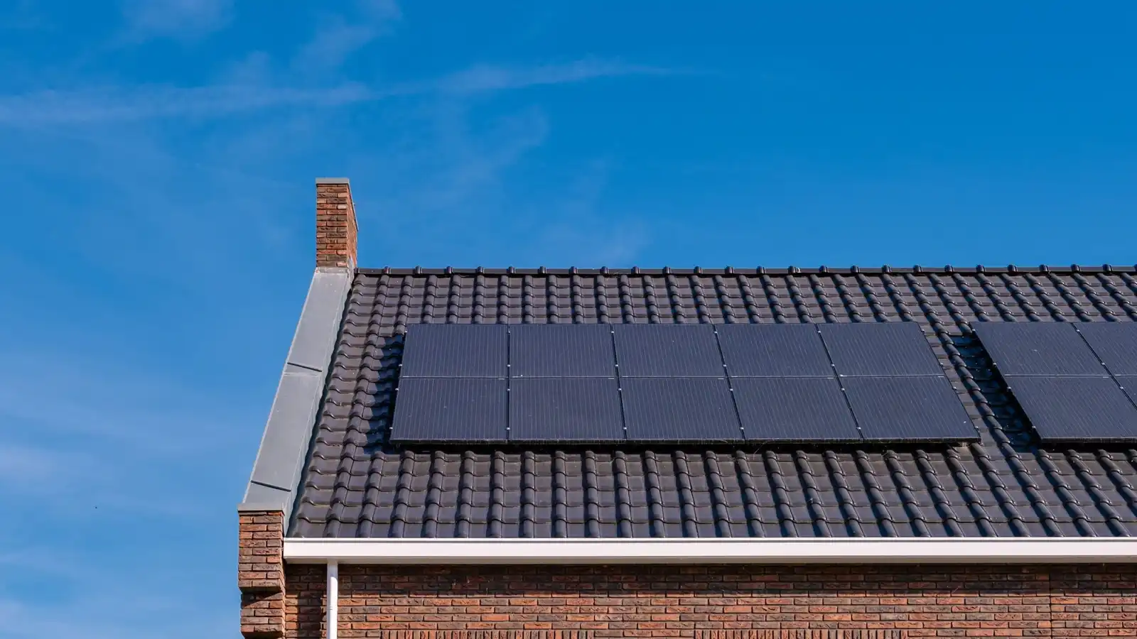 Solar panels on the tiled roof of a brick house, seen from below